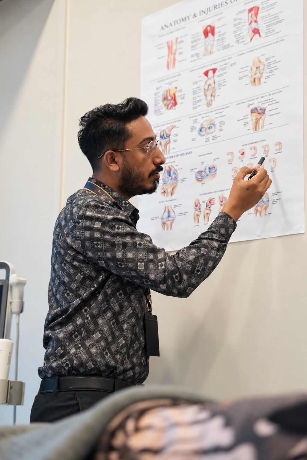 Dr. Shaha explaining joint anatomy on a wall chart